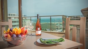 A table with a fruit bowl, a wine bottle, and a glass on a balcony overlooking a scenic view. - Prestige City 2 (Primorsko)