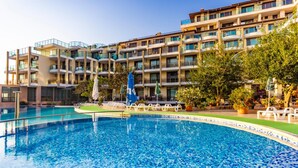 A hotel with a swimming pool, outdoor seating, and a multi-story building with balconies. - Prestige City 2 (Primorsko)