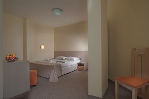 Una habitación de hotel con cama, mesita de noche, silla y frutero.