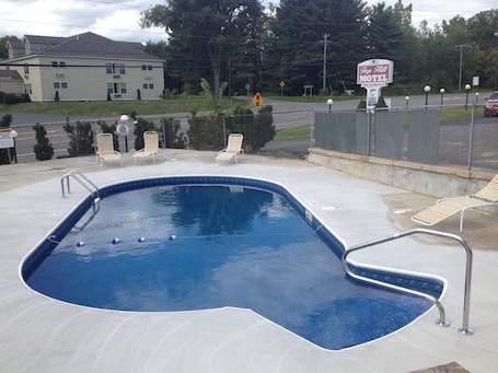 Una piscina al aire libre, sillones reclinables de piscina