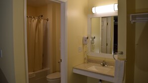 Een badkamer met douche, toilet, wastafel en spiegel.