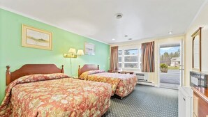 Een hotelkamer met twee bedden, een bureau, een stoel, een televisie en een raam met gordijnen.