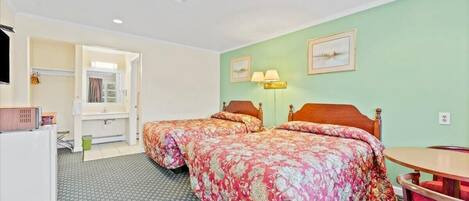 A hotel room with two beds, a desk, a chair, a lamp, and a picture on the wall.