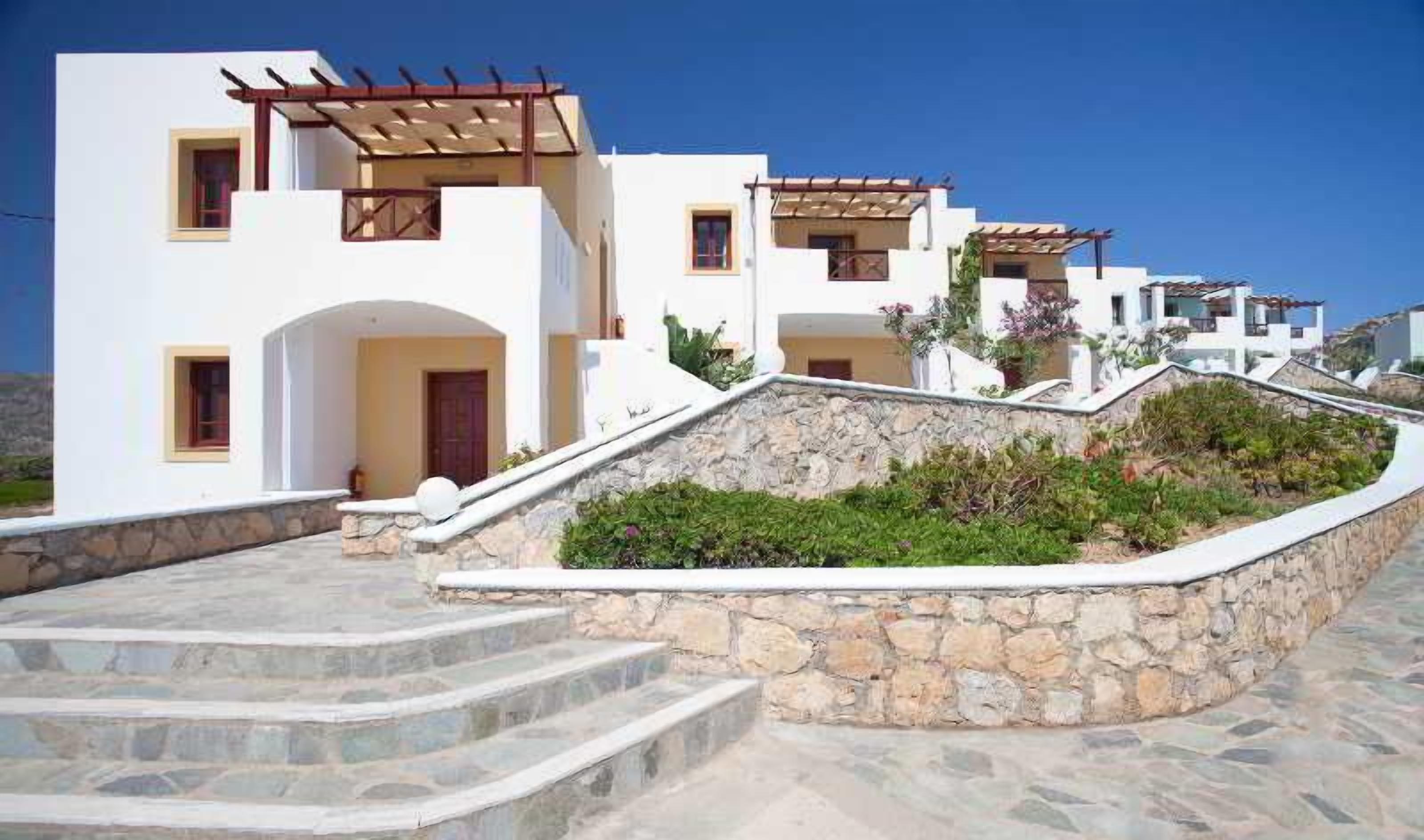 Un bâtiment blanc doté de nombreuses fenêtres et d’un escalier en pierre menant à une porte.