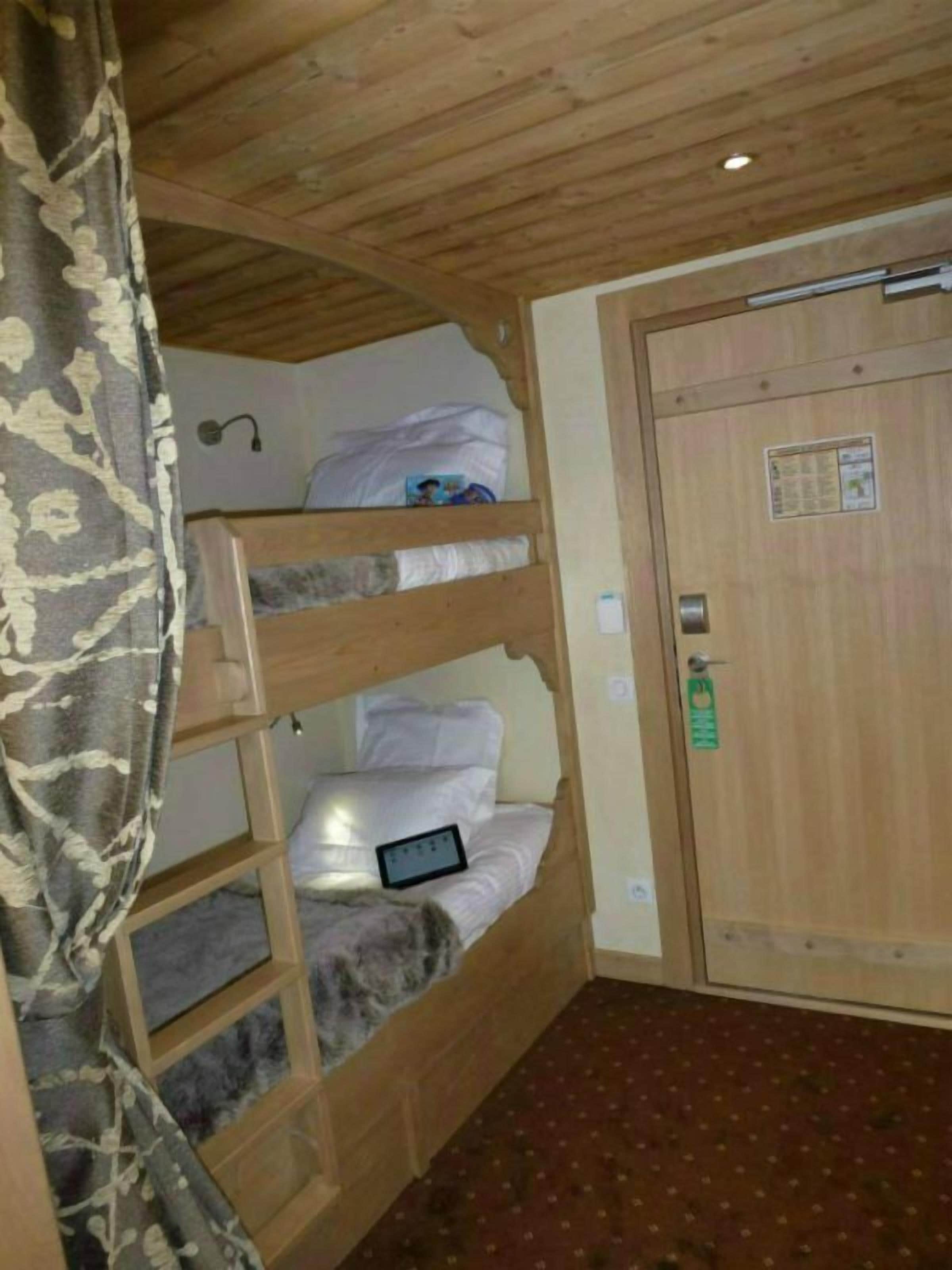 A bunk bed room with a wooden ceiling and a door with a lock.