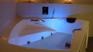 A large, rectangular jacuzzi with a built-in heater, a control panel, and a small shelf with candles. - Hôtel Restaurant Les Sapins Wellness & Gourmet (Manigod)