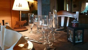 A dining table set with clear glassware, a wooden chair, a lamp, and a decorative cow figurine. - Hôtel Restaurant Les Sapins Wellness & Gourmet (Manigod)