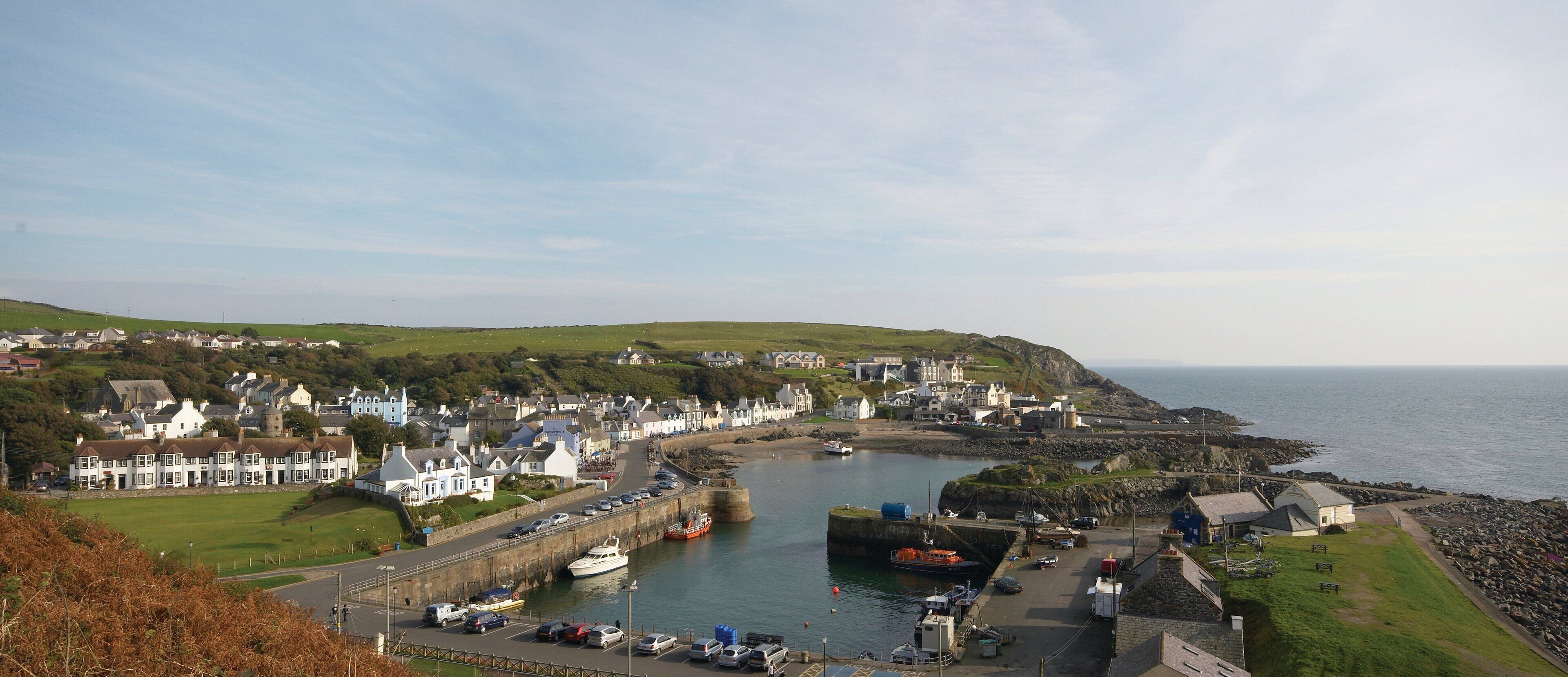 A coastal town with a harbor, stone walls, and a mix of residential and commercial buildings.