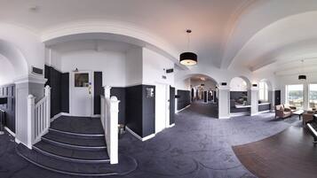 A grand hotel lobby with a grand piano, a staircase, and a view of the city.
