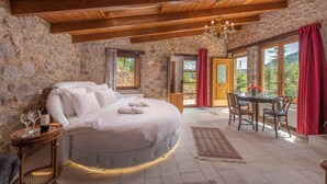 Une chambre avec un grand lit, une table à manger avec des chaises, et une vue sur l’extérieur grâce à de grandes fenêtres.