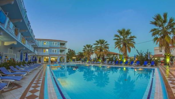A swimming pool with lounge chairs and palm trees. - Sunshine (Zakynthos)