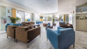A spacious lobby with multiple seating areas, large windows offering views of the outside, and a clean, modern design. - Sunshine (Zakynthos)