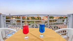 A table with a beige tablecloth, two glasses of red and blue drinks, and a white chair. - Sunshine (Zakynthos)