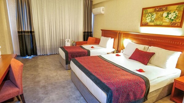 A hotel room with two beds, a wooden headboard, a painting on the wall, and a window with curtains.