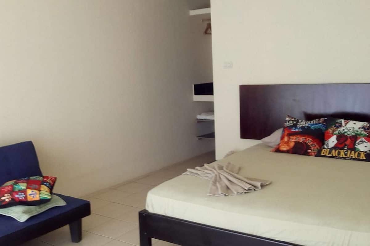 A bedroom with a bed, a chair, and a wall-mounted shelf.