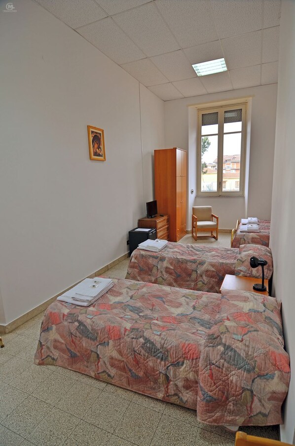 Una habitación con dos camas, una silla, un armario y una ventana.
