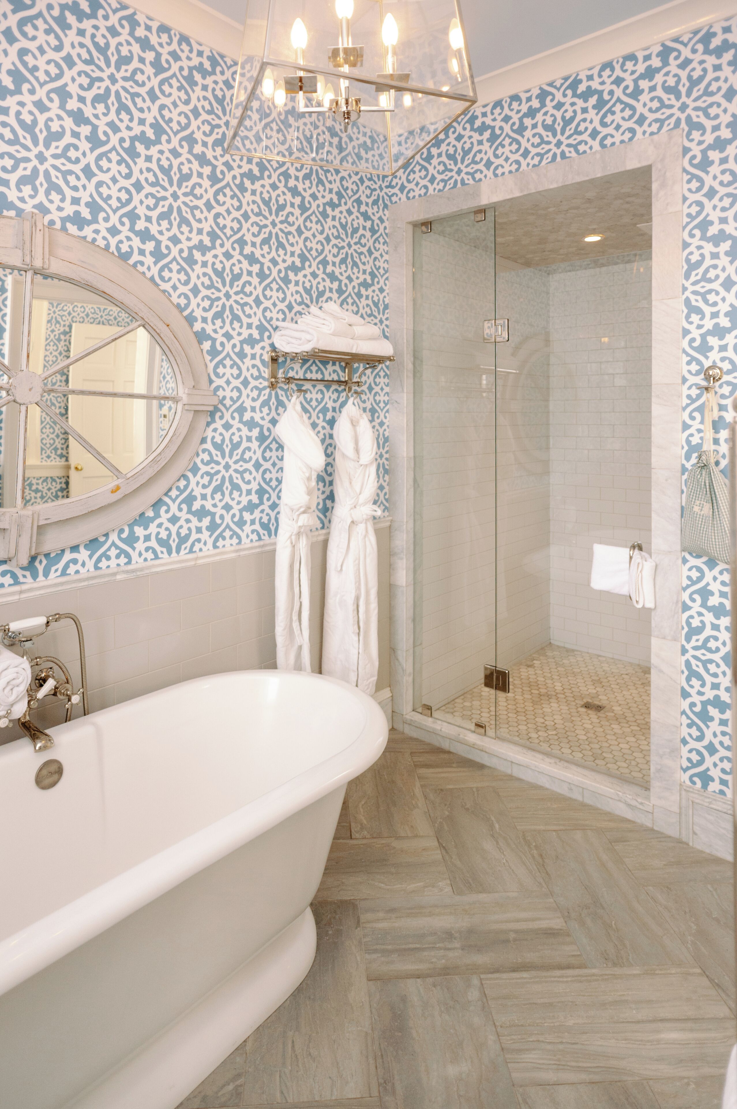 A bathroom with a freestanding bathtub, a glass-enclosed shower, and patterned walls.