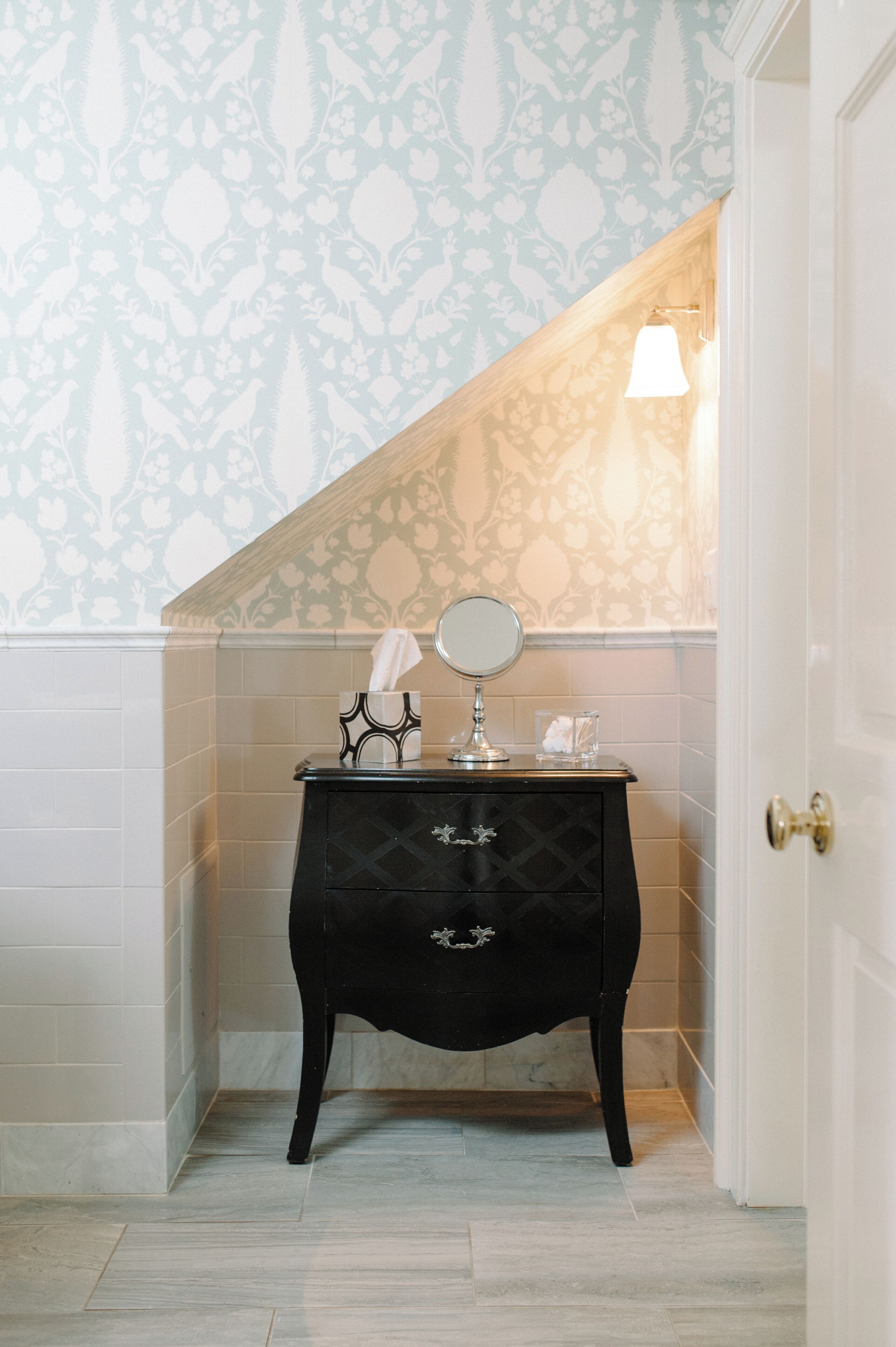 A bathroom with a black vanity, a mirror, and a tissue box.