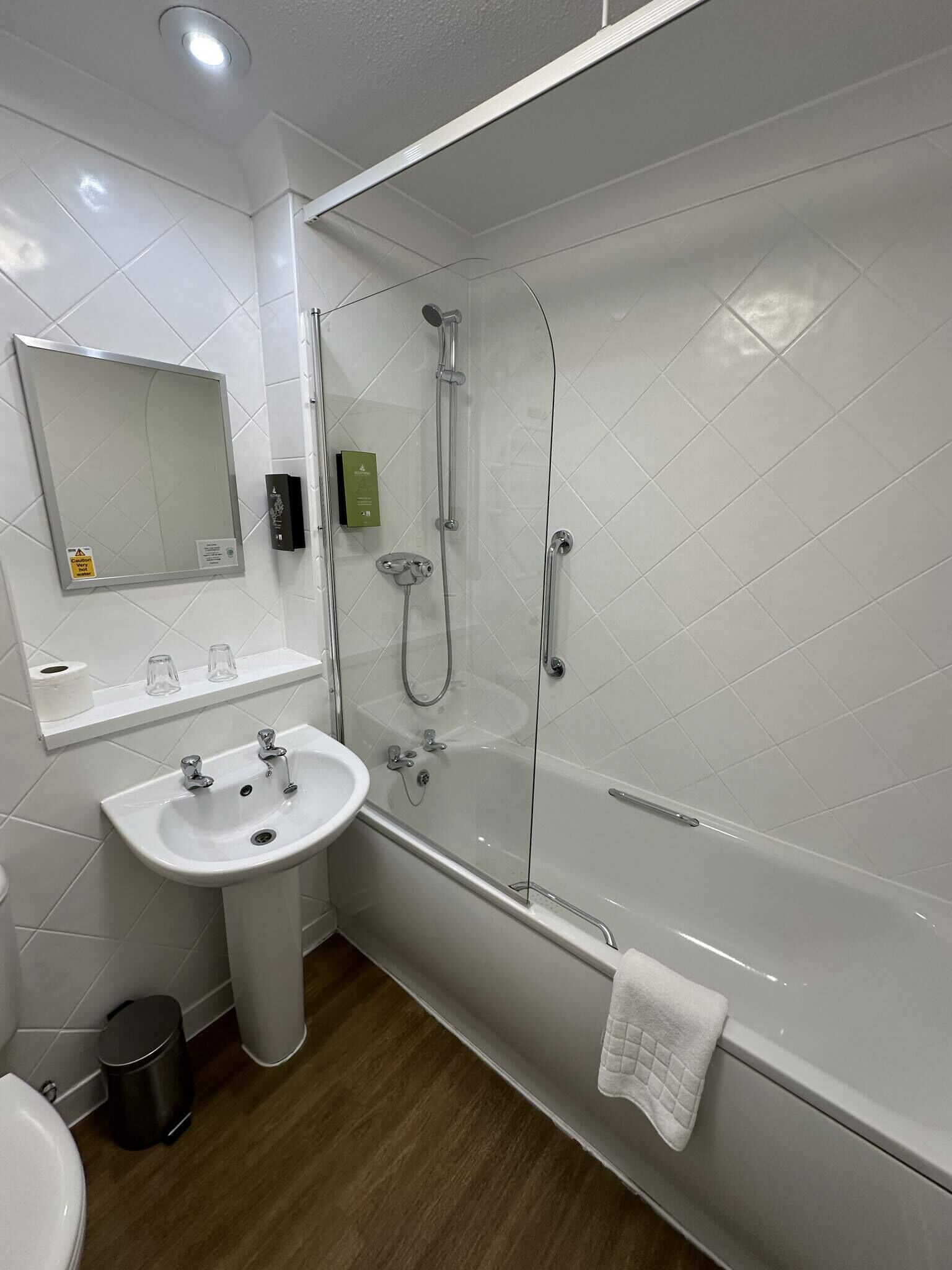 A modern bathroom with a glass-enclosed shower, a pedestal sink, and a mirror above the sink.