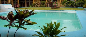 A swimming pool with a clear blue water surface, surrounded by lush green plants and a well-maintained lawn. - Hotel del Valle (El Naranjo)
