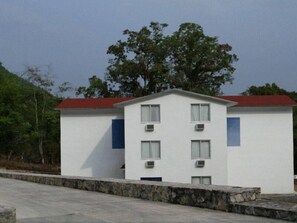 Un edificio de dos plantas con techo rojo, paredes blancas y varias ventanas.