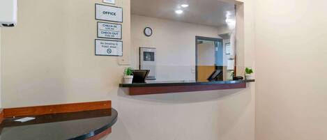A reception area with a reception desk, a clock, and a sign indicating check-in and check-out times.