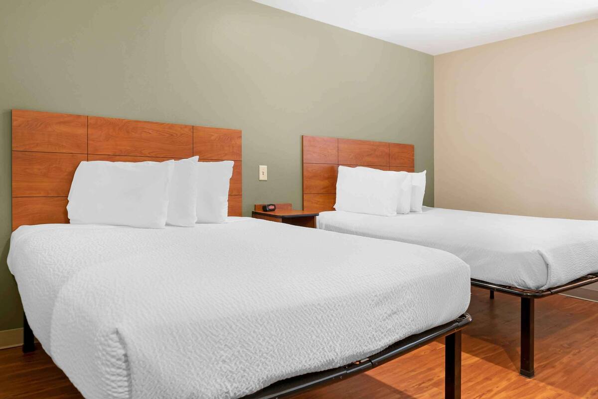 Two single beds with wooden headboards, white bedding, and a wooden floor.