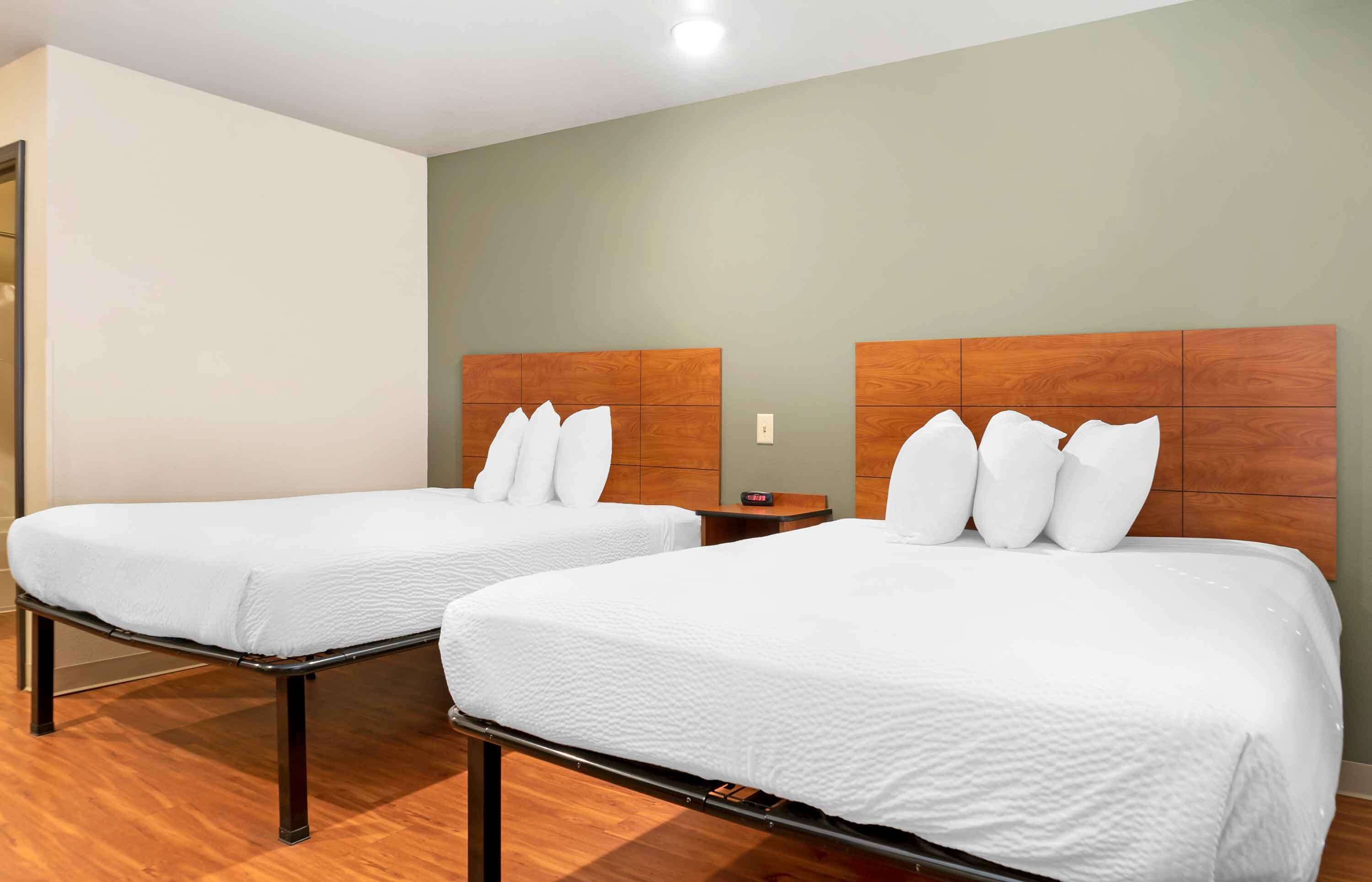 Twee enkele bedden met houten hoofdborden en witte lakens in een hotelkamer.