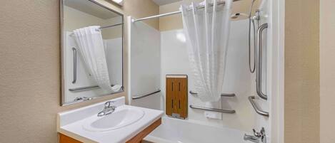 A bathroom with a sink, mirror, shower, and bathtub.