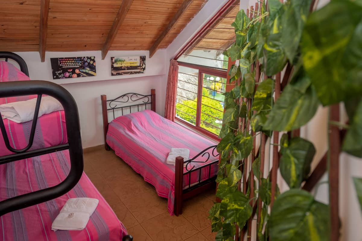 A bedroom with a bed, a window, and a wall with a poster.