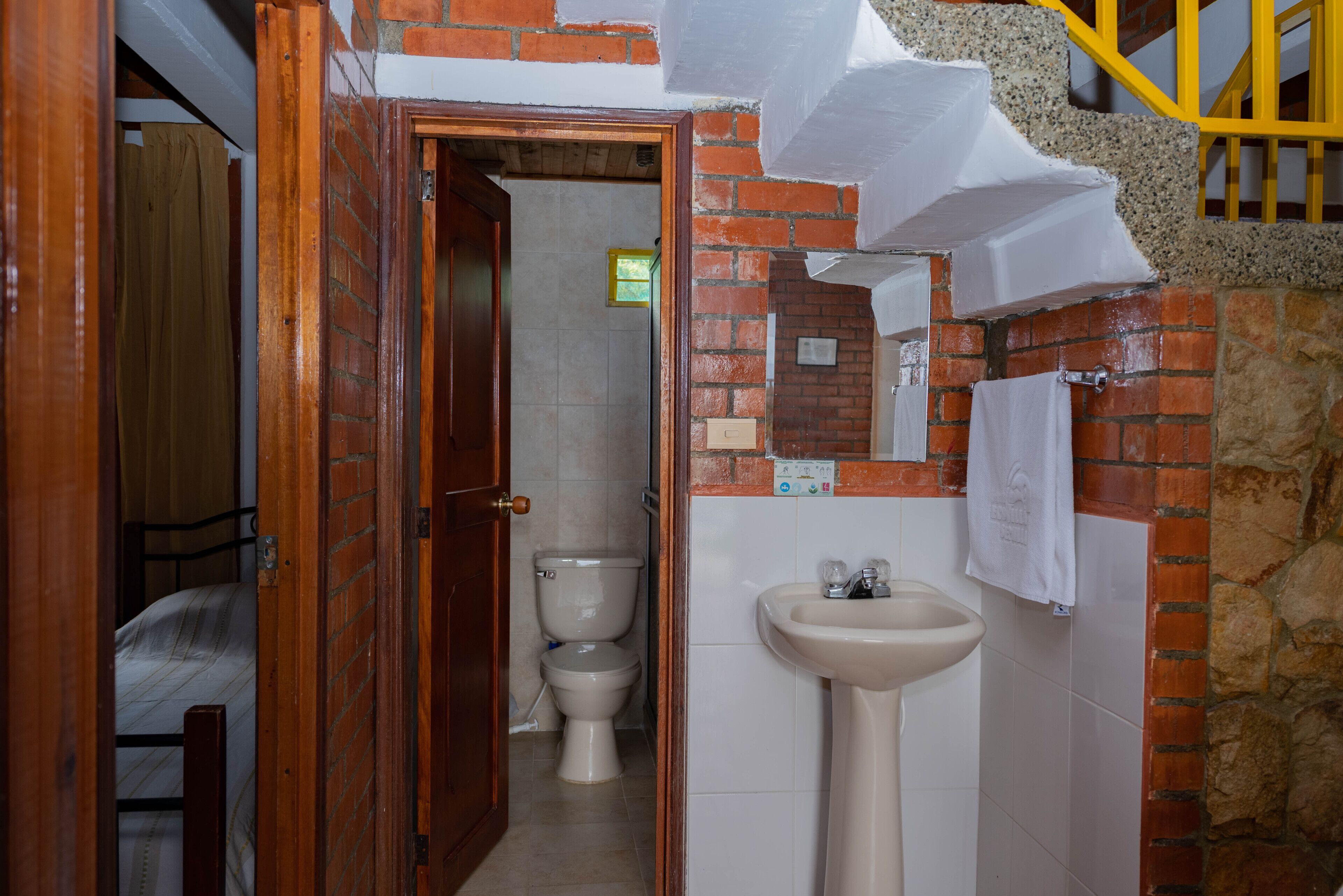 A narrow hallway with a wooden door leading to a bathroom containing a toilet and a sink.