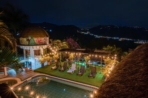 Zona de piscina con sillones de descanso y una estructura abovedada con un mural.