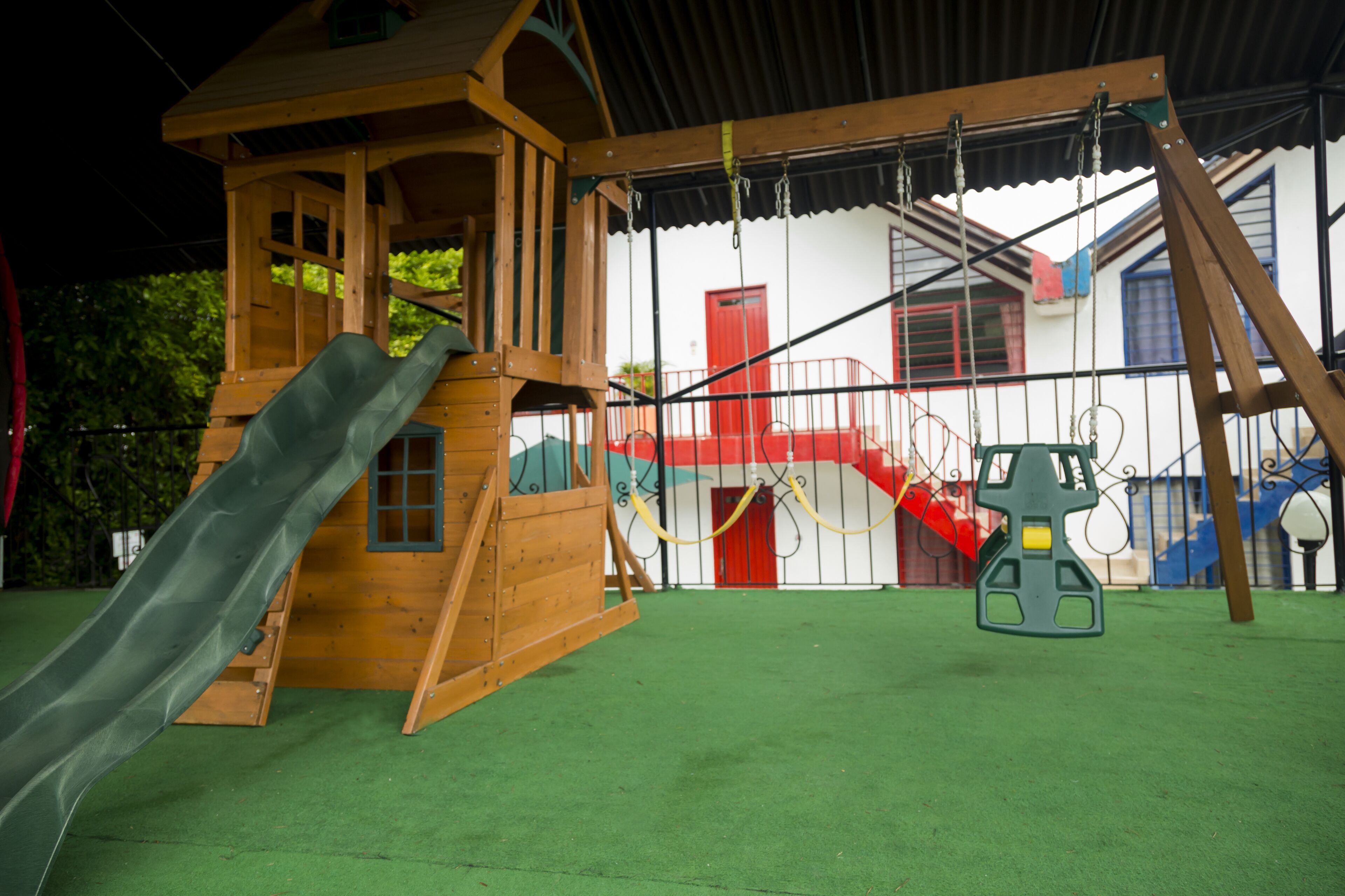 Une cabane en bois pour enfants, avec un toboggan et un portique.