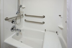 Un baño con bañera, barras de apoyo y cabezal de ducha.