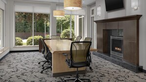 A conference room with a large table, chairs, a fireplace, and a TV mounted on the wall. - Hilton Garden Inn Greensboro Airport (Greensboro)