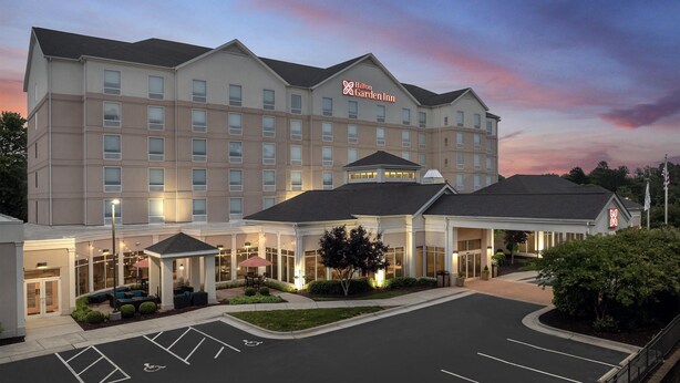 A multi-story hotel with a garden inn sign, a covered entrance, and a parking lot with handicapped accessibility. - Hilton Garden Inn Greensboro Airport (Greensboro)