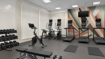 A gym with treadmills, elliptical machines, dumbbells, and benches.