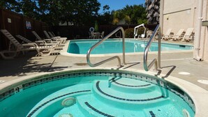 Una piscina con borde de azulejos, una escalera metálica y sillas de descanso.