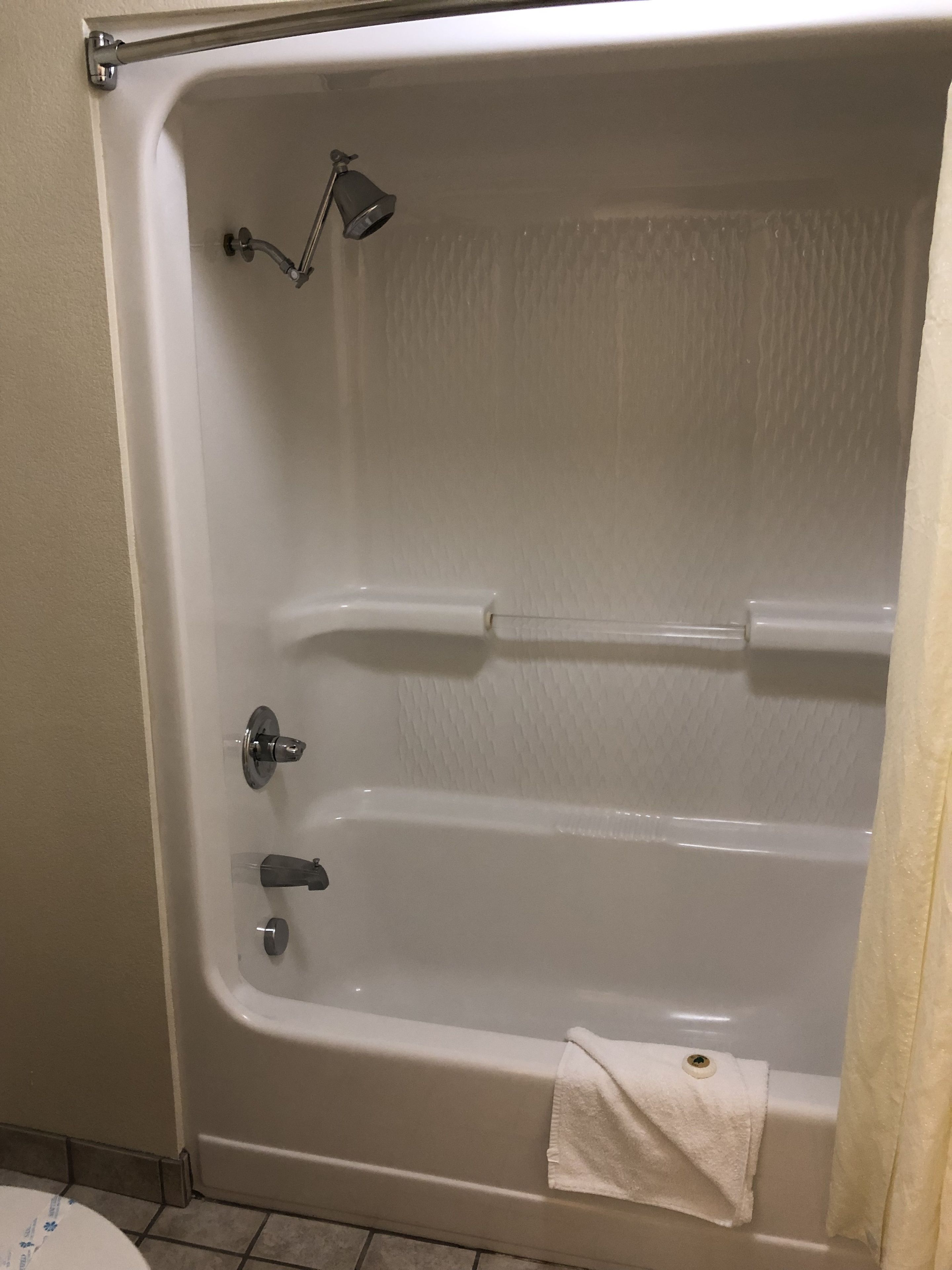 A white bathtub with a showerhead, a towel rack, and a handheld showerhead.