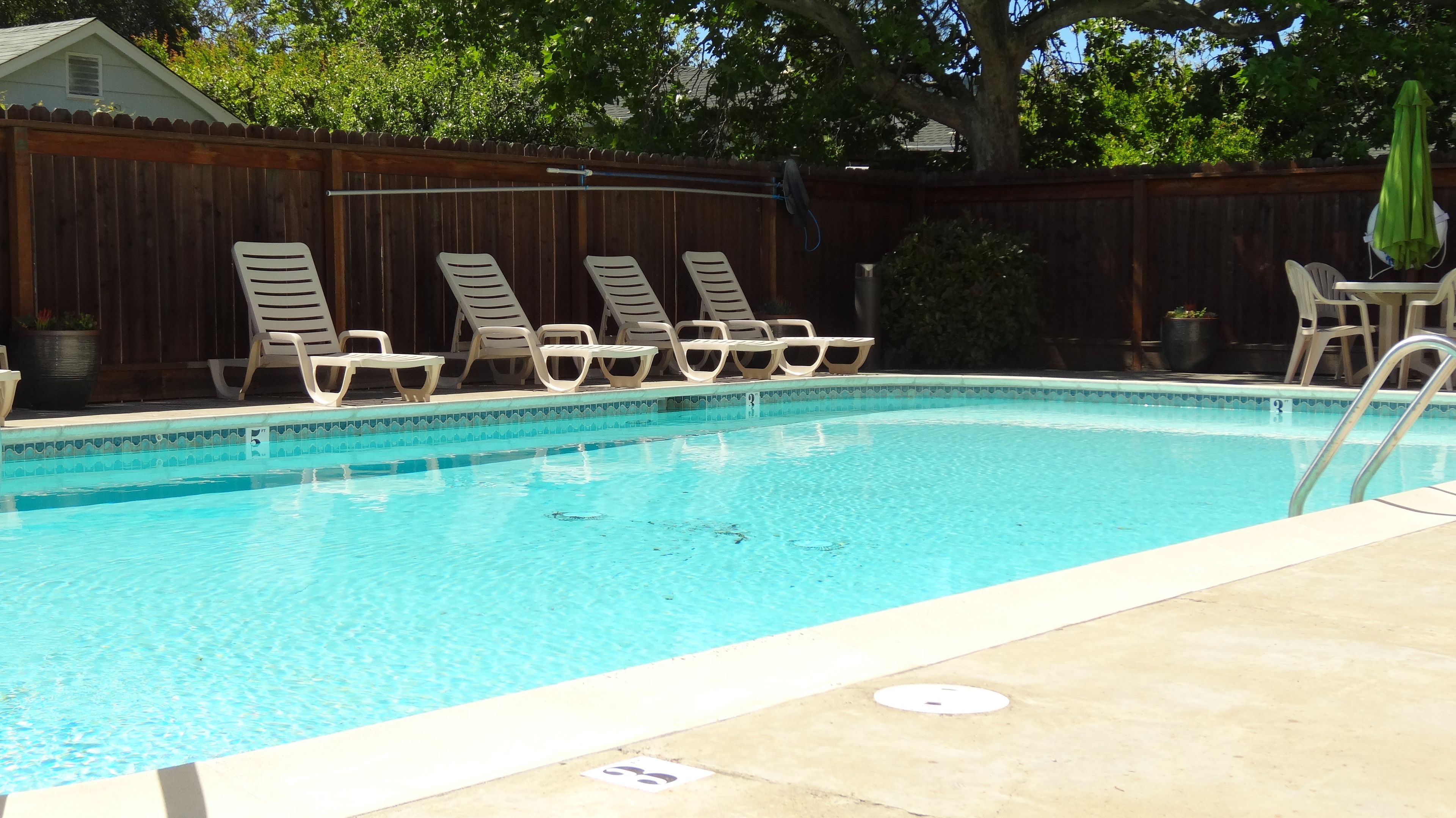 Une piscine avec des chaises longues et une clôture en bois en arrière-plan.