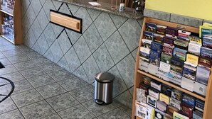 Zona de recepción con suelo de baldosas, mostrador de recepción, un reloj y una exhibición de folletos turísticos.