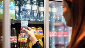 A person selecting bottled water from a refrigerated display. - ibis budget Bern Expo (Bern)