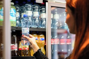 A person selecting bottled water from a refrigerated display. - ibis budget Bern Expo (Bern)