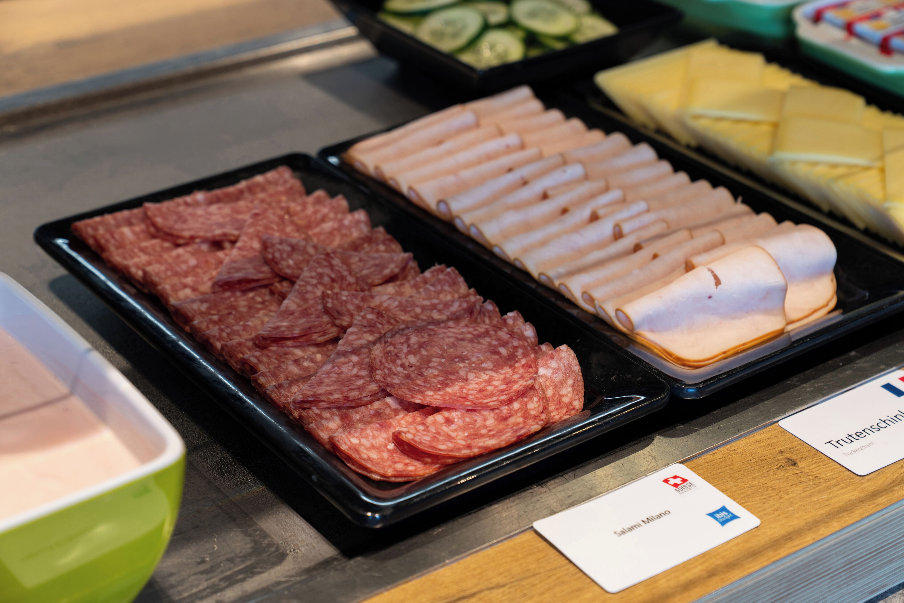 A buffet with various food items including sliced meats and cheeses.