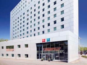 A modern hotel building with a glass entrance, a sign for ibis budget, and a clear blue sky. - ibis budget Bern Expo (Bern)