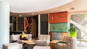Un área de estar moderna con sofás, otomanas y una zona de bar con un colorido mural.