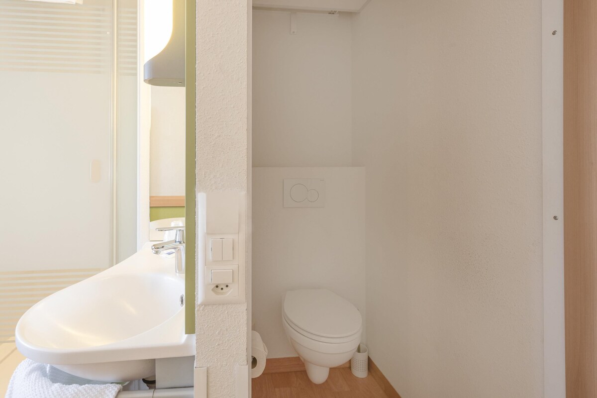 A small, clean bathroom with a sink, toilet, and a mirror.