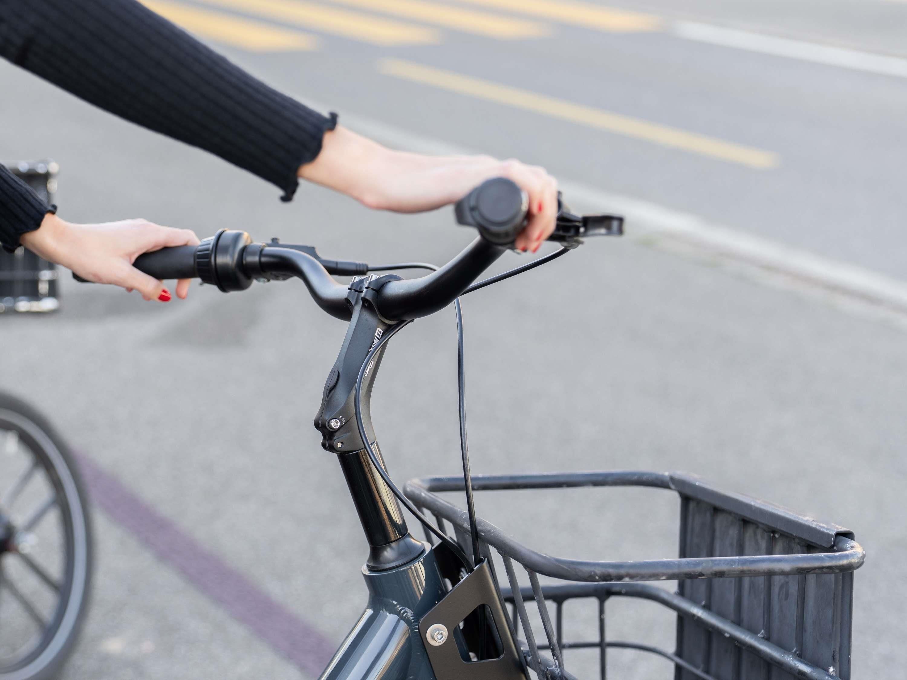 A close-up of a bicycle handlebar with a basket attached.