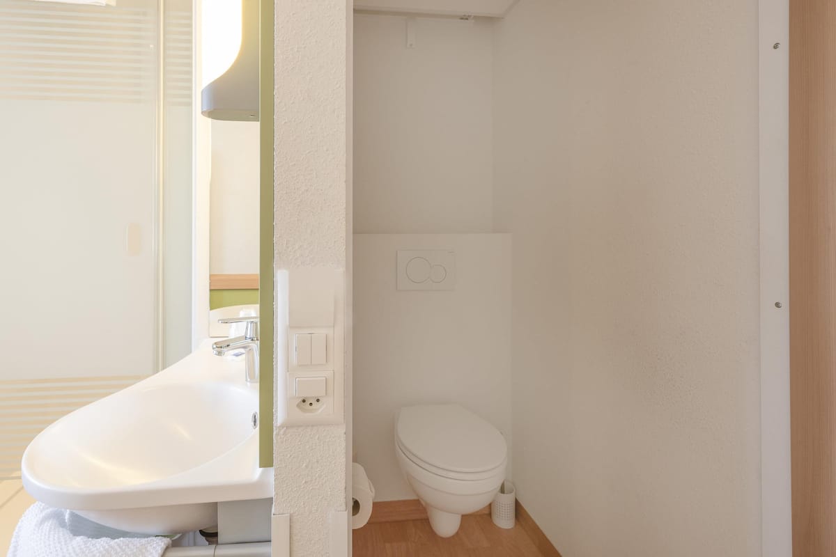 A small, clean bathroom with a sink, toilet, and a mirror.