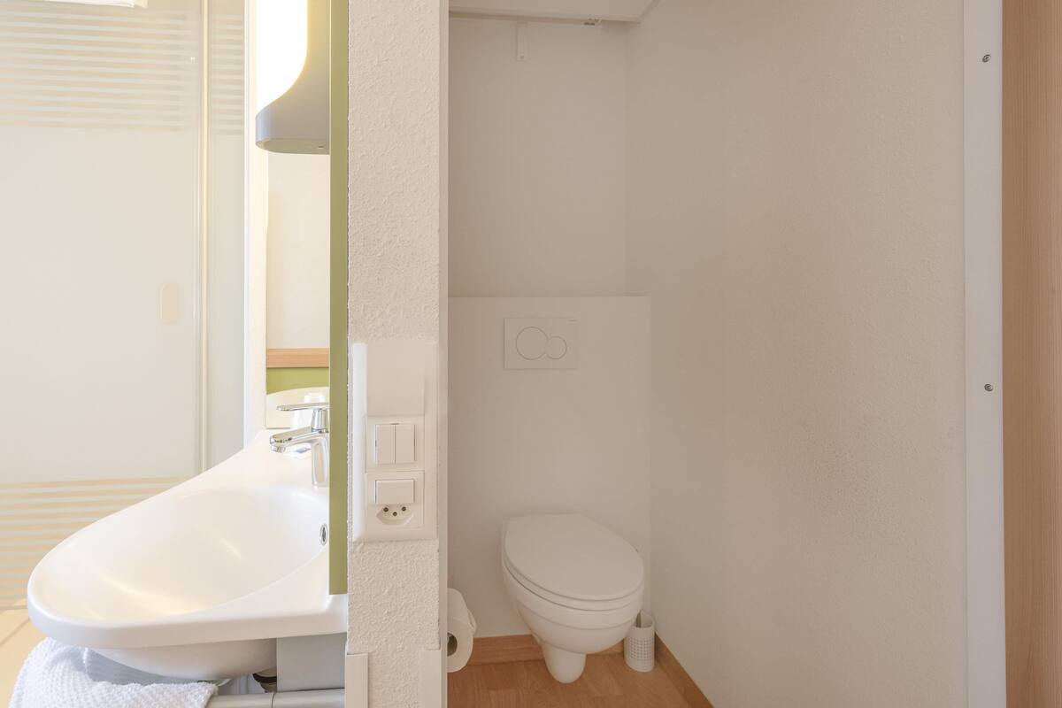 Un baño pequeño y limpio, con lavamanos, inodoro y espejo.